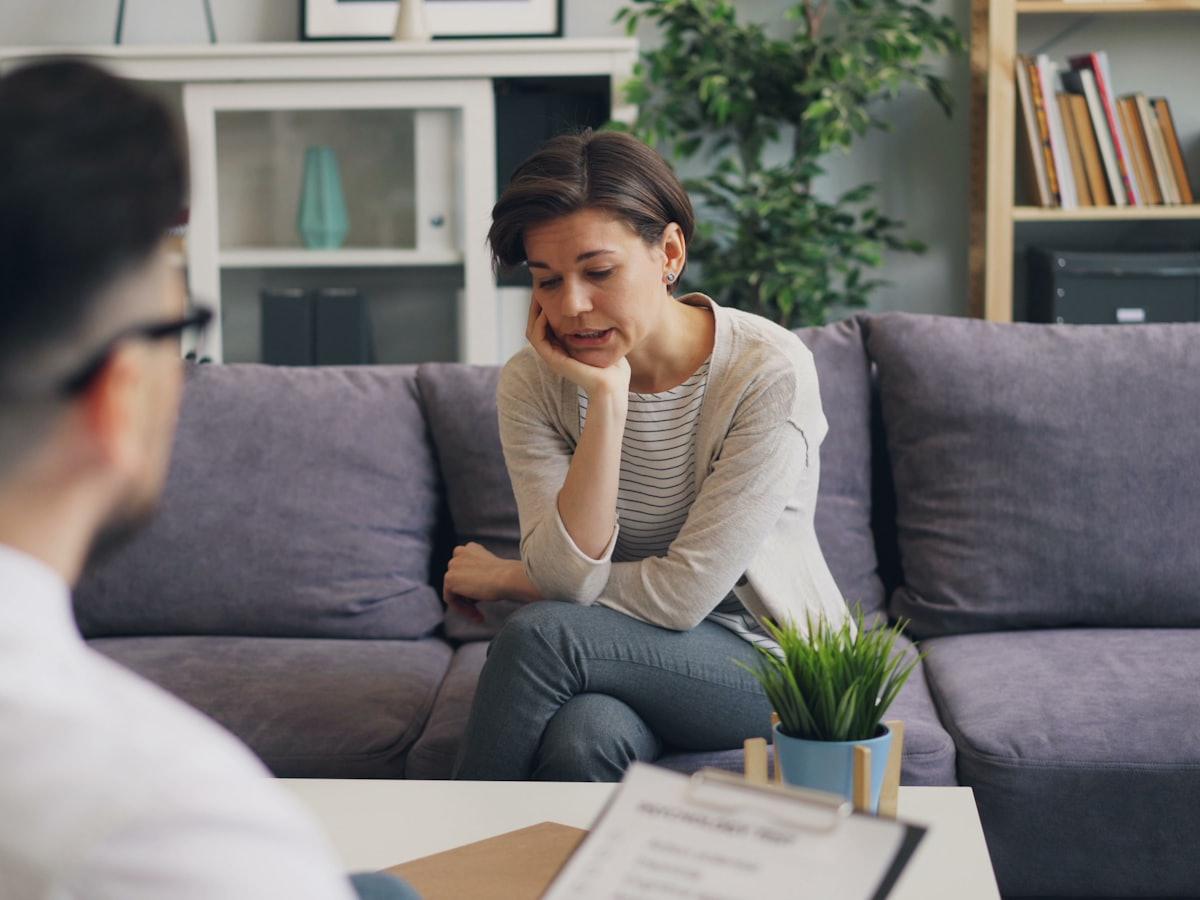 Een hulpverlener met een vragenlijst in gesprek met een cliënt op een bank.