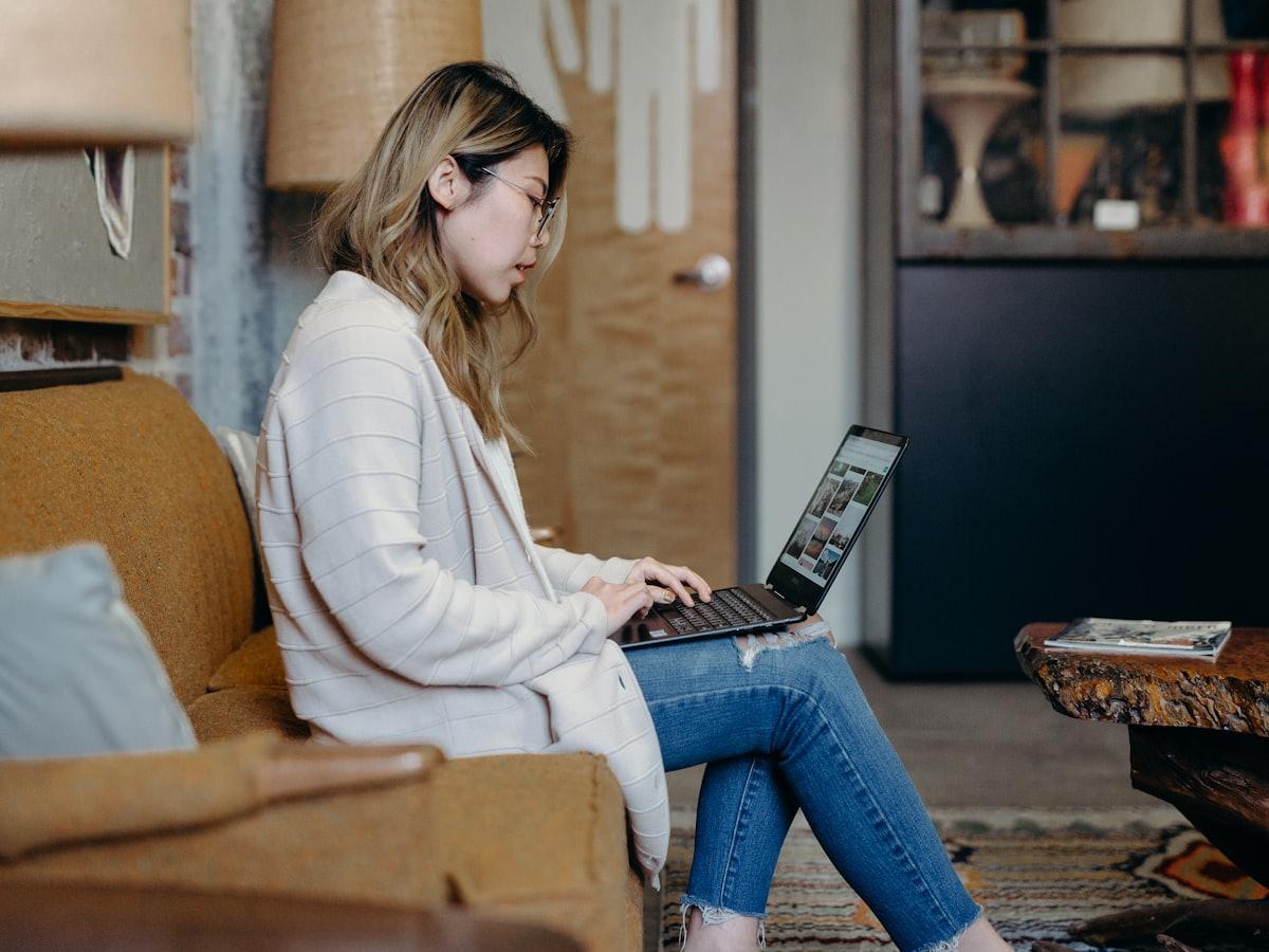 Iemand werkt thuis op een laptop in een warme woonkamer.
